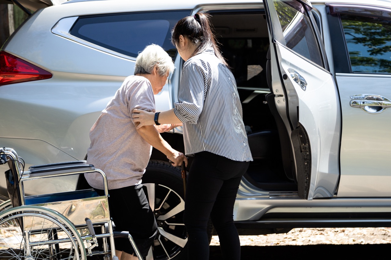 Caregiver helping client into vehicle